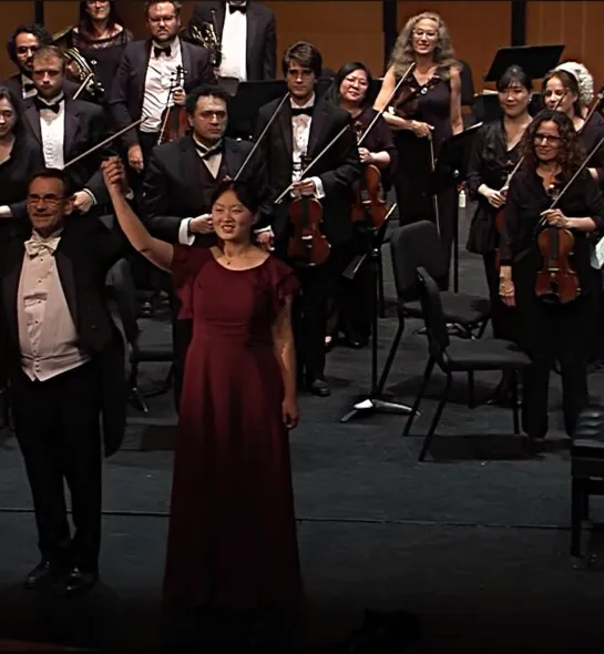 Caroline Su on stage in front of an orchestra